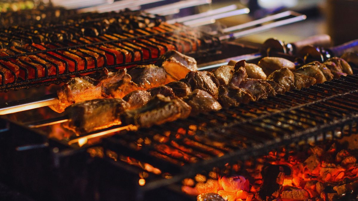 Espetos de carne assando na grelha sobre brasas de carvão